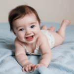 A cute baby with a big smile, crawling on a cozy blanket.