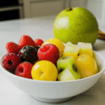 A bowl of fresh fruit featuring assorted colorful fruits on a kitchen counter.