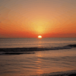 A breathtaking sunset casting vibrant colors over a tranquil ocean horizon.