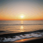 A calm ocean horizon beautifully lit by the colorful hues of the setting sun.