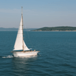 A classic sailboat embarks on an adventure across a calm sea, blending serenity with nautical exploration.