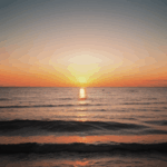 Calm sea at sunset with the horizon reflecting warm, vibrant colors.