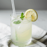 Glass of lemonade with ice, adorned with fresh mint sprigs.