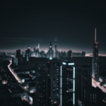 City lights casting a vibrant glow over a modern urban landscape at night.