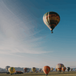 A colorful hot air balloon soaring majestically through the clear blue sky, offering a breathtaking aerial view.