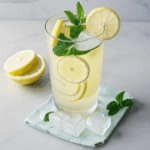 Chilled lemonade in sunlight, with mint and ice cubes.