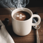 Cozy winter drinks featuring a mug of hot chocolate topped with whipped cream and a sprinkle of cocoa powder.