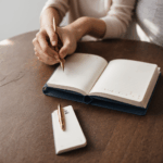 Close-up of hands writing in a journal, symbolizing creativity and personal growth.