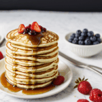 A delightful stack of pancakes with syrup cascading down the sides, surrounded by fresh, juicy berries for a perfect morning meal.