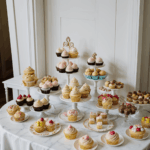 A vibrant dessert table filled with a variety of colorful cupcakes, each uniquely decorated with frosting and sprinkles, enticing for any sweet tooth.