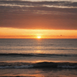 A dreamy view of the ocean at sunset, with the sky ablaze in vibrant hues.