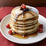 A plate of fluffy pancakes adorned with syrup and fresh berries, capturing the essence of a perfect breakfast.