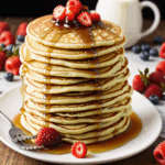 Close-up of fluffy pancakes adorned with vibrant fresh berries and syrup, creating a sweet and enticing breakfast treat.