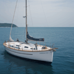 Gentle waves guide a classic sailboat on a serene journey, highlighting the timeless beauty of sailing.