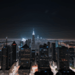 A city skyline glowing brilliantly against the darkness, with lights that outline the silhouette of towering buildings.