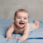 A happy infant crawling joyfully on a cozy blanket.