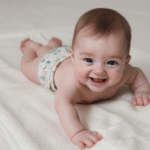 An adorable infant playing and smiling on a soft blanket.