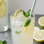 A tall glass of lemonade, packed with ice and mint leaves.