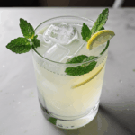 Mint-infused lemonade in a glass, with ice and lemon slices.