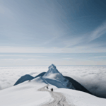 Majestic alpine view of a snow-capped mountain surrounded by clouds, showcasing the splendor of mountainous terrains.