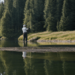 A man connecting with nature while fishing at a serene lake.