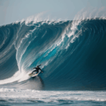 An adrenaline-fueled moment of a surfer navigating a massive ocean wave, showcasing surfing skills.