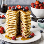 A beautifully styled plate of pancakes crowned with syrup and colorful berries, inviting a scrumptious brunch experience.
