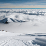 A striking view of a mountain rising above the clouds, depicting the grandeur of alpine landscapes under a clear sky.