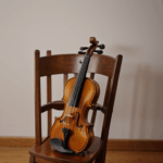 A violin on a wooden chair, creating a timeless scene of musical inspiration.