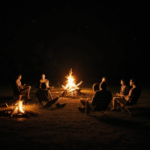 Nighttime gathering of friends around a glowing campfire.