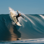 A majestic ocean wave crests as a surfer takes on the thrilling challenge, embodying the spirit of adventure and surf culture.