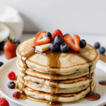 Fluffy pancakes covered in syrup and a colorful mix of berries, providing a delicious start to the day.