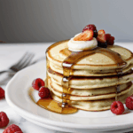 A delectable arrangement of pancakes with syrup and fresh berries, perfect for satisfying morning cravings.