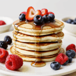 A pancake stack with syrup and vibrant berries, capturing the essence of a perfect breakfast or brunch.