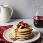 A stack of pancakes drizzled with syrup and topped with an assortment of fresh berries, ideal for a morning feast.