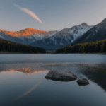 A peaceful dawn landscape with a mountain lake reflecting the vibrant colors of sunrise, surrounded by majestic peaks and serene beauty.
