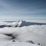 A tranquil scene of a mountain enveloped by clouds, highlighting the peacefulness of untouched natural wonders.