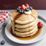 A delicious stack of pancakes with syrup and fresh berries, promising a satisfying and flavorful morning treat.