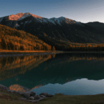 A picturesque sunrise view of a mountain lake, with tranquil waters and vibrant colors creating a scene of natural beauty and serenity.