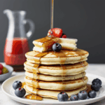 Close-up of a pancake stack with syrup and berries, showcasing a delicious and inviting breakfast option.