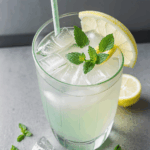 A refreshing glass of lemonade with ice cubes and a sprig of mint, showcasing a delightful summer drink.