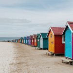 Seaside views of colorful beach huts with waves crashing nearby