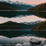 A serene mountain lake at sunrise with calm waters and vibrant colors.