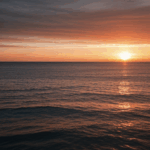 Serene seaside sunset with the horizon painted in warm, vibrant colors.