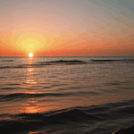 Serene scenes of a sunset casting golden hues over a calm ocean surface.