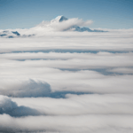 A breathtaking view of snowy mountain peaks rising above the clouds, showcasing nature's grandeur and serene beauty.