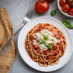 A plate of delicious spaghetti topped with rich tomato sauce, garnished with fresh herbs.
