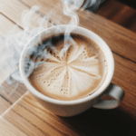 A close-up of a steaming coffee cup, emitting a rich aroma on wood.
