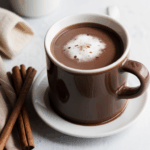 A steaming mug of hot chocolate with whipped cream and chocolate shavings, perfect for warming up on a cold day.