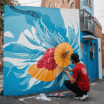 A street artist skillfully painting a colorful mural on a city wall, showcasing urban creativity and artistic expression.